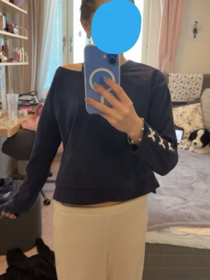Mörkblå croppad topp med snörning - Snygg mörkblå lite croppad topp med långa ärmar och vit snörningsdetalj vid ärmsluten. Toppen har en lös passform och bred halsringning som ger en avslappnad vibe. Är i barnstolen men skulle säga den passar XS💞 passa på att köp, en supersöt tröja!!🥹 skriv om frågor 😋