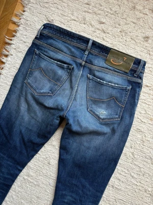 Jacob Cohën ”Nick” - Ett par extremt feta Cohën jeans i en av de nyaste slimfit modellerna nämligen ”Nick” som har ett nypris på över 3000 kr! Några få slitningar från fabrik på ena låret. Slitningarna på knät har tyg bakom. Hör av dig vid frågor!