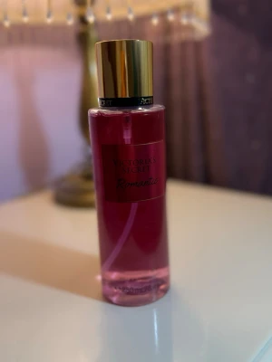 Victoria's Secret Romantic parfym - En snygg parfym från Victoria's Secret i doften Romantic. Flaskan är cylinderformad i genomskinligt rosa plast med guldfärgat lock och svart etikett. Perfekt för dig som gillar fräscha och blommiga dofter.