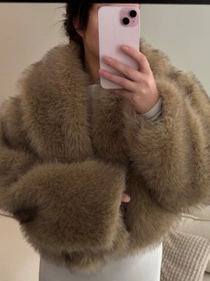 Beige fluffig pälsjacka - Supersnygg beige pälsjacka med oversized passform och bred krage. Jackan har långa ärmar och är gjord i ett mjukt, fluffigt material som ger en lyxig känsla. Perfekt för att hålla värmen under kalla dagar och ger en trendig look.