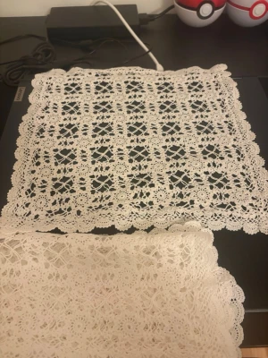 Vita virkade dukar i spetsmönster - Två vita fyrkantiga dukar med detaljerat virkade spetsmönster och vågig kant. Perfekta som dekoration på bord eller hylla. Klassisk design med blommiga och geometriska inslag i mönstret.