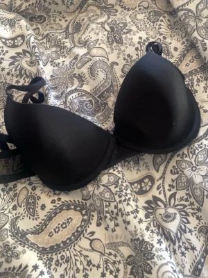 Svart bh - Snygg bh med vadderade kupor och justerbara axelband. Klassisk design utan synliga detaljer eller spets. Perfekt för dig som vill ha extra stöd och lyft under tröjan.