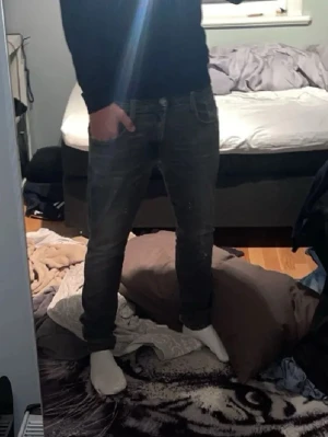 Mörkgrå jeans med vita sömmar - Säljer ett par mörkgrå jeans med vita kontrastsömmar och klassisk femficksmodell. Jeansen har en rak passform och detaljerade bakfickor. Perfekta för dig som gillar en avslappnad men ändå stilren look.