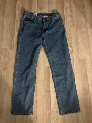Blå raka jeans från Lee - Klassiska blå jeans från Lee med rak passform och fem fickor. Jeansen har en tidlös tvätt och är tillverkade i slitstarkt denimtyg. Perfekta för dig som gillar en enkel och clean stil.