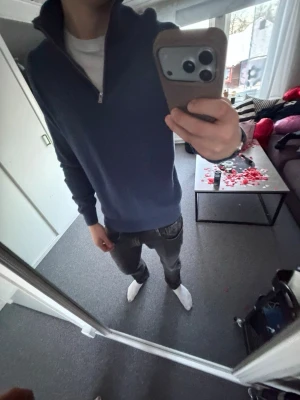 Mörkblå halvzip tröja - Mörkblå långärmad tröja med halv dragkedja och hög krage. Tröjan har en enkel och stilren design, perfekt att bära över en t-shirt. Materialet ser mjukt och bekvämt ut, och passformen är något slim.