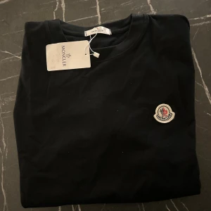Svart Moncler t-shirt strl m -  Moncler Tshirt Strl M Svart, aldrig använd inga slitage eller liknande. Väldigt fin och fräsch!   Finns i Stockholm, kan mötas upp samt fraktas!