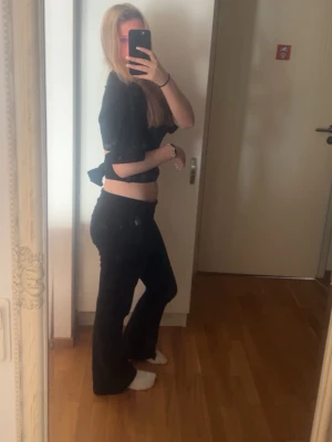 Svart croppad topp med knyt - Säljer en svart croppad topp med korta ärmar och knyt i ryggen. Toppen har en enkel och stilren design som passar perfekt till både jeans och kjol. Materialet känns mjukt och bekvämt mot huden.