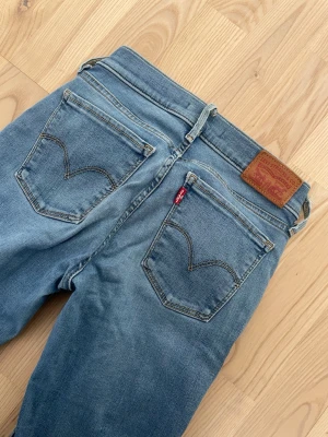 Levi's blå 710 Super Skinny Jeans - Säljer ett par klassiska blå skinny jeans från Levi's Jeansen har en smal passform och är tillverkade i mjukt denimtyg med lätt tvättad look och röda Levi's-taggen på bakfickan. Storlek 24