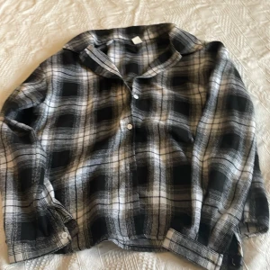 Svartvit rutig skjorta - Säljer en svartvit rutig skjorta med klassisk krage och knappar framtill. Skjortan har långa ärmar och är tillverkad i ett mjukt tyg som känns skönt mot huden. Perfekt för dig som gillar en avslappnad men ändå stilren look.