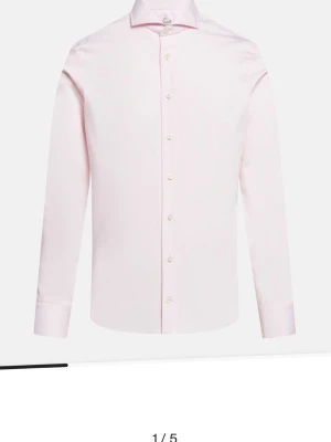 Ljusrosa skjorta från Van Laack - Ordinarie pris 1800 kronor. Jag säljer en stilren ljusrosa skjorta från Eton med klassisk krage och knappar framtill. Skjortan är långärmad och har en slim passform som sitter snyggt på kroppen. Perfekt för dig som vill ha en enkel men elegant look. Har alla storlekar ifrån 38-45 centimeter, pris kan variera ifrån olika storlekar 