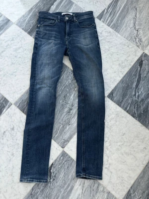 Mörkblå jeans  - Snygga blå slim fit jeans från Calvin klein med klassisk femficksdesign och diskreta slitningar framtill. Jeansen har raka ben och kontrastsömmar samt logga på bakfickan. Perfekta för en avslappnad och trendig look.