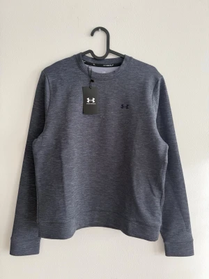 Under Armour UA Drive Midlayer Crew, Ny med lapp - Under Armour UA Drive Midlayer Crew i damstorlek M. Helt ny med lappen kvar.  Sportig och stilren midlayer i stretchigt, följsamt material som andas och håller värmen utan att bli klumpig. Framtagen för golf men passar lika bra till träning, promenader eller som snygg vardagströja.  Mjuk insida och lätt tekniskt material som ger en bekväm passform.  • Märke: Under Armour • Modell: UA Drive Midlayer Crew • Storlek: M (Women) • Skick: Ny med lapp • Färg: Mörkgrå melerad  Nypris 999 kr.
