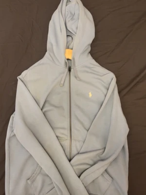 Ralph Lauren zip hoodie - Säljer en ljusblå hoodie från Polo Ralph Lauren zip hoodie i riktigt fet unik colorway. Cond 8/10, inga slitage bara en tvätt behövs.