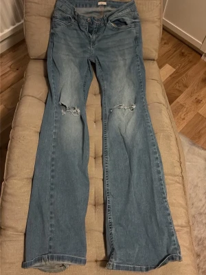 Lågmidjade ljusblåa Jeans Nelly - Säljer ett par ljusblå bootcut jeans från Nelly, lite slitage längst ner på byxorna eftersom dem är lite för långa för mig men annars inget annat slitage!