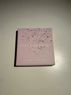Steve Laurant Celebration Edition ögonskugga - Steve Laurant Celebration Edition ögonskuggspalett med 9 färger. Paletten har en snygg ljuslila förpackning med glittriga detaljer och stilren design. Perfekt för dig som vill ha en trendig och lyxig look till ögonen.