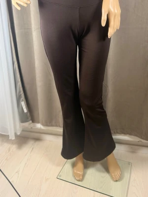 Bruna bootcut leggings - Snygga bruna leggings med bootcut-modell och hög midja. Tillverkade i ett stretchigt och mjukt material som sitter skönt på kroppen. Perfekta för dig som vill ha en trendig och bekväm look.