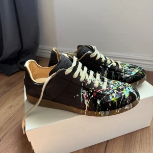 Maison Margiela sneakers med färgstänk - Säljer ett par riktigt schyssta Maison Margiela Replica pain splatter. Skorna är i nyskick och endast använda 2 gånger. Storlek 41 och sitter riktigt bra. Kan lösa schysst pris vid snabb affär😀