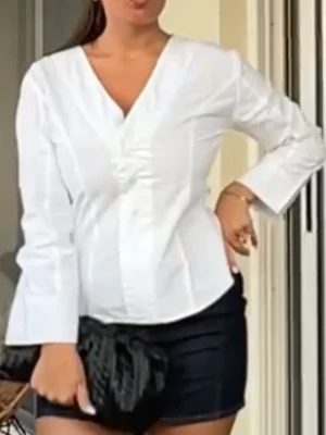 Vit blus från Gina Tricot - Snygg vit figursydd skjorta från Gina Tricot med v-ringning och knäppning framtill. Blusen har långärmade ärmar och är tillverkad i ett lätt material som ger en stilren look. Perfekt att matcha med jeans eller kjol för en trendig outfit.