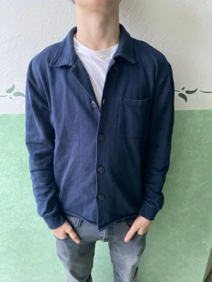 Mörkblå Overshirt från Riley  - Snygg mörkblå skjortkofta med krage och knäppning framtill. Tröjan har en bröstficka och långa ärmar. Tillverkad i mjukt bomullsliknande material som känns bekvämt mot huden. Perfekt för lager på lager och enkel att matcha.