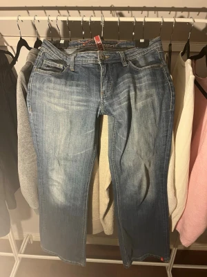 Blå bootcut jeans från Esprit - Snygga blå jeans från Esprit med bootcut passform och låg midja. Jeansen har ljusa slitningar och broderade detaljer på bakfickorna. 