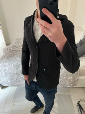 Svart kavajjacka med huva från Oscar Jacobson - Väldigt snygg kavaj liknande jacka från Oscar Jacobson. Jackan är som ny om den ens är använd. (Sorry för dåliga bilder men varje gång jag tog en bild så blev det konstigt med ljuset.    ——————————————————————————                                                    📐| Storlek: S                                                          👖| Märke: Oscar Jacobson                                  🔎| Skick: Som ny                                                    💵 | Ny Pris: 3999kr       