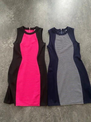 Två korta klänningar från H&M - Säljer två snygga korta klänningar från H&M. Ena är svart med ceriserosa mittpanel och ribbad struktur, den andra är marinblå med vit- och marinblått randigt mönster framtill. Båda är ärmlösa och har dragkedja bak. Perfekta för dig som vill sticka ut! Endast 100 kr för båda 