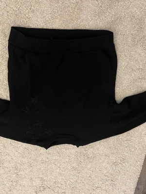 Svart tröja med stjärndetaljer - Snygg svart tröja med rund halsringning och dekorativa stjärnor i små svarta nitar på ena axeln. Tröjan har långa ärmar och är gjord i ett mjukt material som känns skönt mot huden. Perfekt för dig som gillar enkla plagg med en twist.