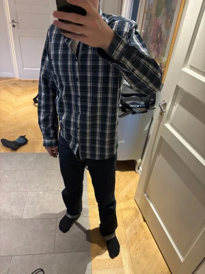 Flanellskjorta från Oscar Copenhagen  - Säljer en klassisk långärmad skjorta i blått, grönt och vitt rutigt mönster. Skjortan har knappar hela vägen fram och en krage. Jag är 182 för referens