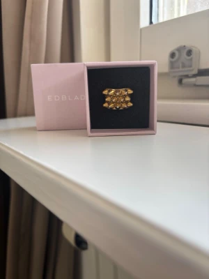 Guldfärgad ring från Edblad -  Säljer en snygg guldfärgad ring från Edblad med taggar. Bred modell som verkligen syns på handen. Storlek 18,5 mm. Pris kan diskuteras.