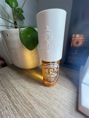 Sol de Janeiro Cheirosa 62 Parfym - Sol de Janeiro Cheirosa 62 är en parfym med en snygg, genomskinlig orange flaska och vit kork. Flaskan har en rundad form och text i vitt. Doften är inspirerad av pistage och saltad karamell, vilket ger en unik och söt känsla.