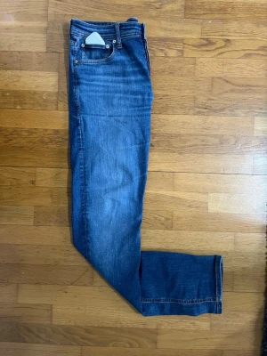 Blå slim fit jeans från Jack & Jones - Säljer ett par klassiska blå slim fit jeans från Jack & Jones. Jeansen har fem fickor, normal midja och dragkedjegylf. Materialet är mjukt denim med lätt stretch för extra komfort. Perfekta till en avslappnad stil.