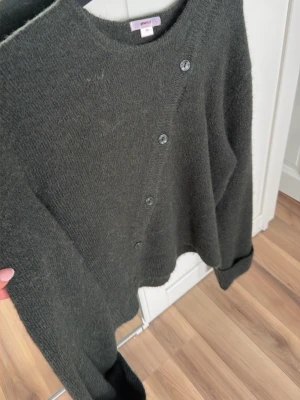 Mörkgrön kofta  - Mysig mörkgrön kofta från Selected Femme med rund halsringning och knappar framtill. Koftan är stickad i ett mjukt material och har långa ärmar. Perfekt för lager på lager och enkel att matcha med olika outfits.