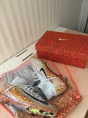 Nike Mercurial Superfly 10 Elite FG Safari Pack - Riktigt feta fotbollsskor med naturgräsdobbar, anvönda endast på naturgräs i storlek 45 (29 cm) Enda defekterna på skorna är hålet i ena strumpan. Det påverkar såklart inte prestationen på skorna. Använda, men har fortfarande riktigt mycket kvar att ge. Köpta från Unisport, alltså 100% legit. Skopåse och original skobox är inkluderade med skorna. Privat meddelande ifall du vill ha mer bilder, priset är inte heller hugget i sten!         
