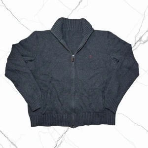 Vintage grovstickad cardigan- herr strl M - Säljer en Ralph Lauren mörkgrå grovstickad zip up tröja i storlek M med vinröd broderad Ralph Lauren logga på bröstet.  👕 Märke: Ralph Lauren 📏 Storlek: M 🎨 Färg: Mörkgrå 🧵 Material: 100% bomull 📐 Mått: 62 cm lång, 56 cm bred 📌 Skick: Mycket bra skick (se bilder) ℹ️ Storleksetikett från Ralph Lauren är borttagen  💬 Hör av dig vid frågor 💰 Pris kan diskuteras vid snabb affär 📦 Skickas inom 24 timmar