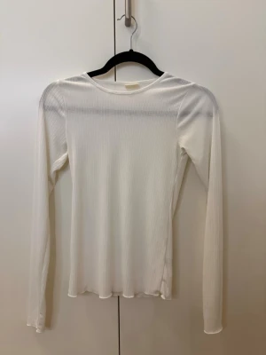 Vit ribbad långärmad Sofie Schnoor - Hej!🌸 Säljer en stilren vit långärmad topp från Sofie Schnoor. Toppen är ribbad med rund halsringning och har en smal passform. Perfekt att styla lager på lager eller bära som den är. Materialet är mjukt och stretchigt för extra komfort. Skriv om det är något ni undrar!!💕