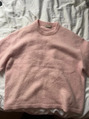 Ljusrosa stickad tröja - Mysig ljusrosa stickad tröja från Gina Tricot med rund halsringning och avslappnad passform. Tröjan har ribbade muddar vid hals, ärmslut och nederkant. Perfekt för lager på lager och enkel att styla till olika looks.