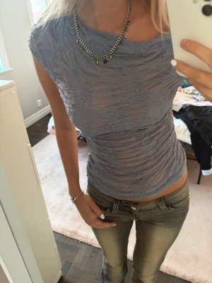 Ljusblå mesh topp med rynk - Säljer en ljuslila mesh topp med rynkade detaljer och tight passform. Toppen har korta ärmar och kan bäras offshoulder för en trendig look. Materialet är tunt och stretchigt, perfekt för att styla med jeans eller kjol.