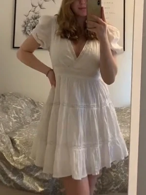 Vit kort klänning med puffärm - Söt vit kort klänning från Zara med puffärmar och v-ringning. Klänningen har volangdetaljer och ett diskret prickigt mönster i tyget. Perfekt för student eller skolavslutning. 