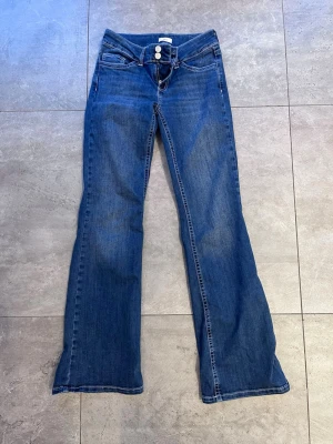 Nelly Low Waist Bootcut Stitch Jeans – EU 38 - Superfina bootcut jeans från Nelly i en klassisk mörkblå tvätt! Dessa jeans har en perfekt låg midja (low waist) och en smickrande passform som släpper snyggt vid knäna. Märke: Nelly Storlek: EU 38 Modell: Low Waist Bootcut Stitch Jeans Detaljer: Dubbelknäppning i midjan, dekorativa sömmar och stretchigt, skönt material. Skick: Nyskick, bara använda 1 gång. Innerbensmåttet är ca 85 cm. 💖 ✨ Fraktar snabbt! Har av dig vid minsta lilla fundering!