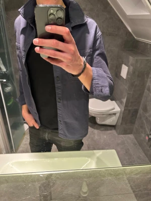 Mörkblå overshirt med stora fickor - Säljer en stilren mörkblå overshirt med klassisk krage och stora bröstfickor. Passar perfekt nu till våren. Den är i riktigt bra skick. Jag på bilden är 188cm. Hör av er vid prisförslag eller frågor:)