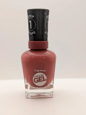Sally Hansen Miracle Gel p-proper rose nagellack 90% kvar - Snyggt gel-nagellack från Sally Hansen i färgen Proper P-rose, en varm rosabrun nyans. Lacket kommer i en klassisk glasflaska med svart lock och är en del av Miracle Gel-serien, vilket ger en glansig finish och lång hållbarhet.