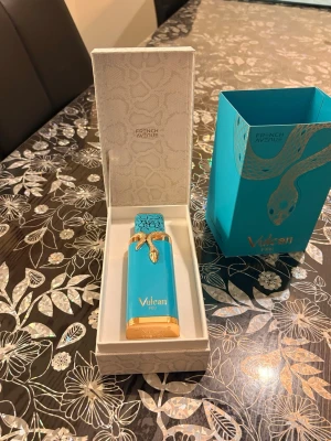 French Avenue Vulcan Feu Eau de Parfum - Lyxig parfym från French Avenue i en turkos flaska med gulddetaljer och ormdekor. Flaskan levereras i en elegant ask med matchande turkos och guld design. Perfekt för dig som gillar unika och snygga parfymflaskor. Nyköpt helt oanvänt.