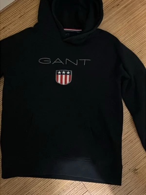 Svart hoodie från GANT med logga 13-14 år 154-160 - Svart hoodie från GANT fraktar samma dag väldigt bra skick 150 kr 
