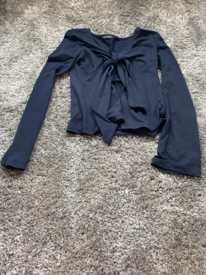 Mörkblå långärmad topp med knyt - Snygg mörkblå långärmad topp från Missay med knyt framtill. Modellen är croppad och har en feminin v-ringning. Perfekt att styla med jeans eller kjol för en trendig look.