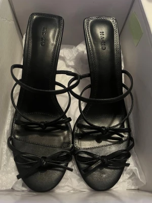 Klackar  - Säljer ett par super snygga rosett klackar från NA-KD. Bekväm klackhöjd på 4cm. Passar perfekt till fest, middagar eller sommarkvällar.  Helt oanvända med prislapp kvar.  Köpta för 600 och helt slutsålda.