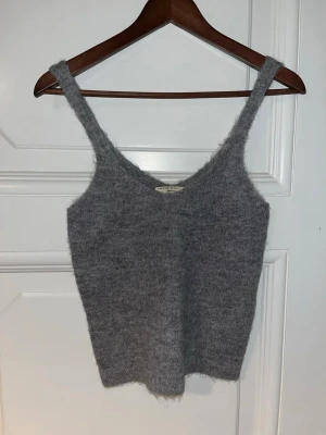 Grå stickad linnetopp från Gina Tricot - Mysig grå stickad linnetopp från Gina Tricot med breda axelband och v-ringad hals. Skriv gärna om ni har några frågor💕