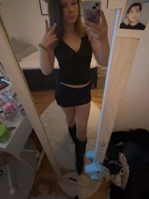 Svart croppad v-ringad topp - Säljer en svart croppad topp med v-ringning och ärmlös design. Perfekt för dig som gillar en stilren och enkel look. Toppens passform är tight och den är gjord i ett mjukt syntetmaterial.