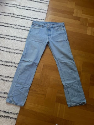 Ljusblå raka jeans från Levi's - Säljer ett par klassiska ljusblå jeans från Levi's med rak passform och fem fickor. Använda väldigt sparsamt över ca 1 år, med inga synliga tecken på slitage. 