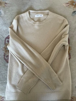 Beige knit från Samsøe Samsøe - Snygg beige stickad tröja från Samsøe Samsøe med rund halsringning och ribbade muddar vid ärmslut och nederkant. Enkel och stilren design som passar till det mesta. Materialet känns mjukt och bekvämt.