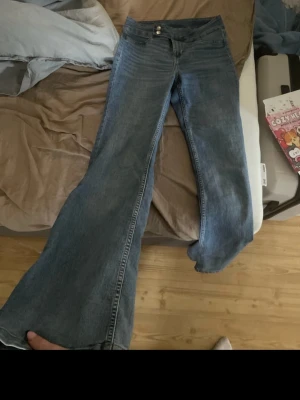 Blå bootcut jeans med hög midja - Säljer ett par klassiska blå bootcut jeans med hög midja och dubbla knappar fram. och är tillverkade i ett mjukt denimtyg. Perfekta för dig som gillar en avslappnad men ändå trendig look. Bilderna är från min vinted sida. 